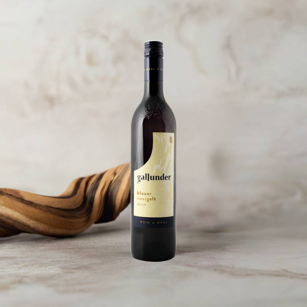 Blauer Zweigelt Weinflasche auf Mamorplatte mit Holzwurzel im Hintergrund.