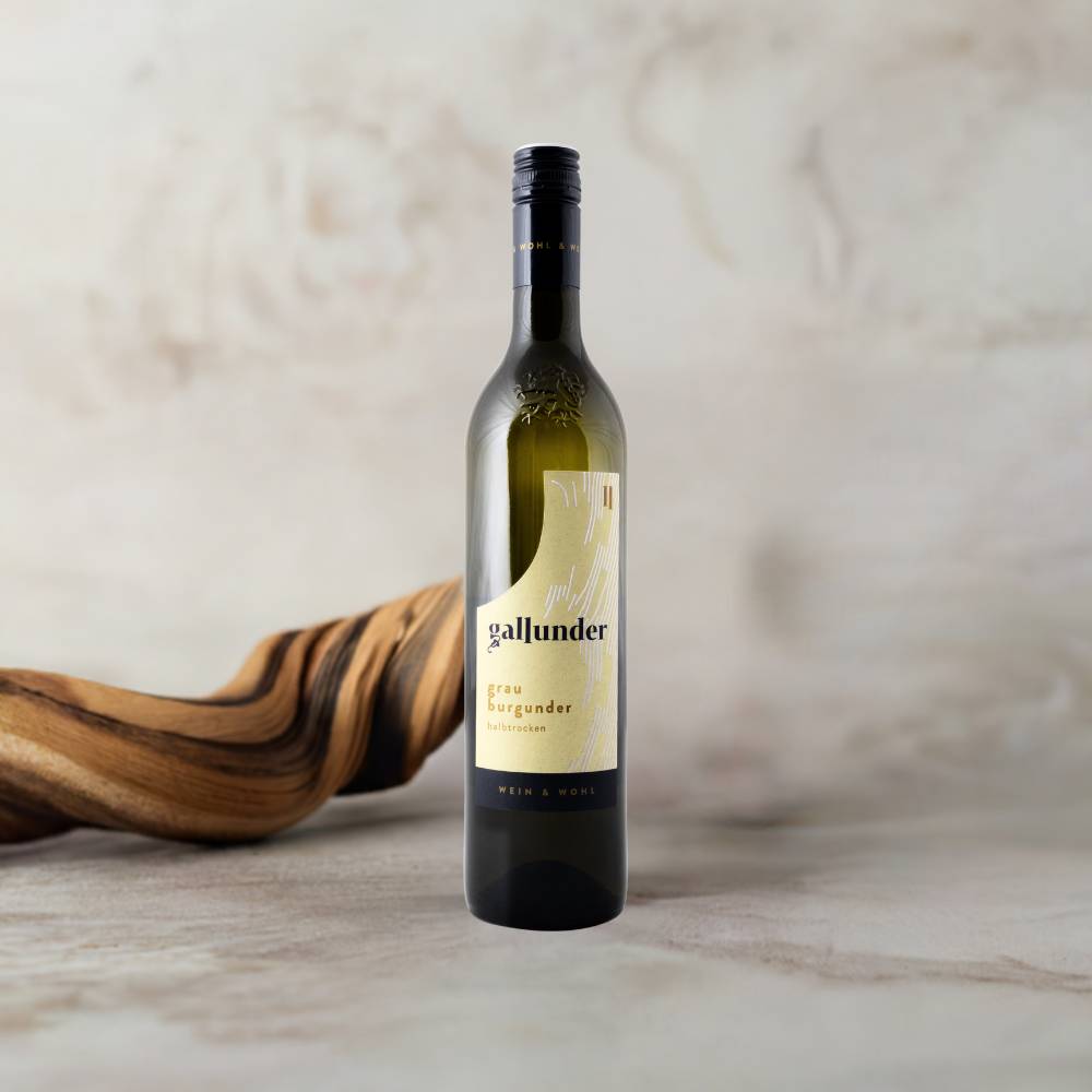 Grauburgunder Weinflasche auf Mamorplatte mit Holzwurzel im Hintergrund.