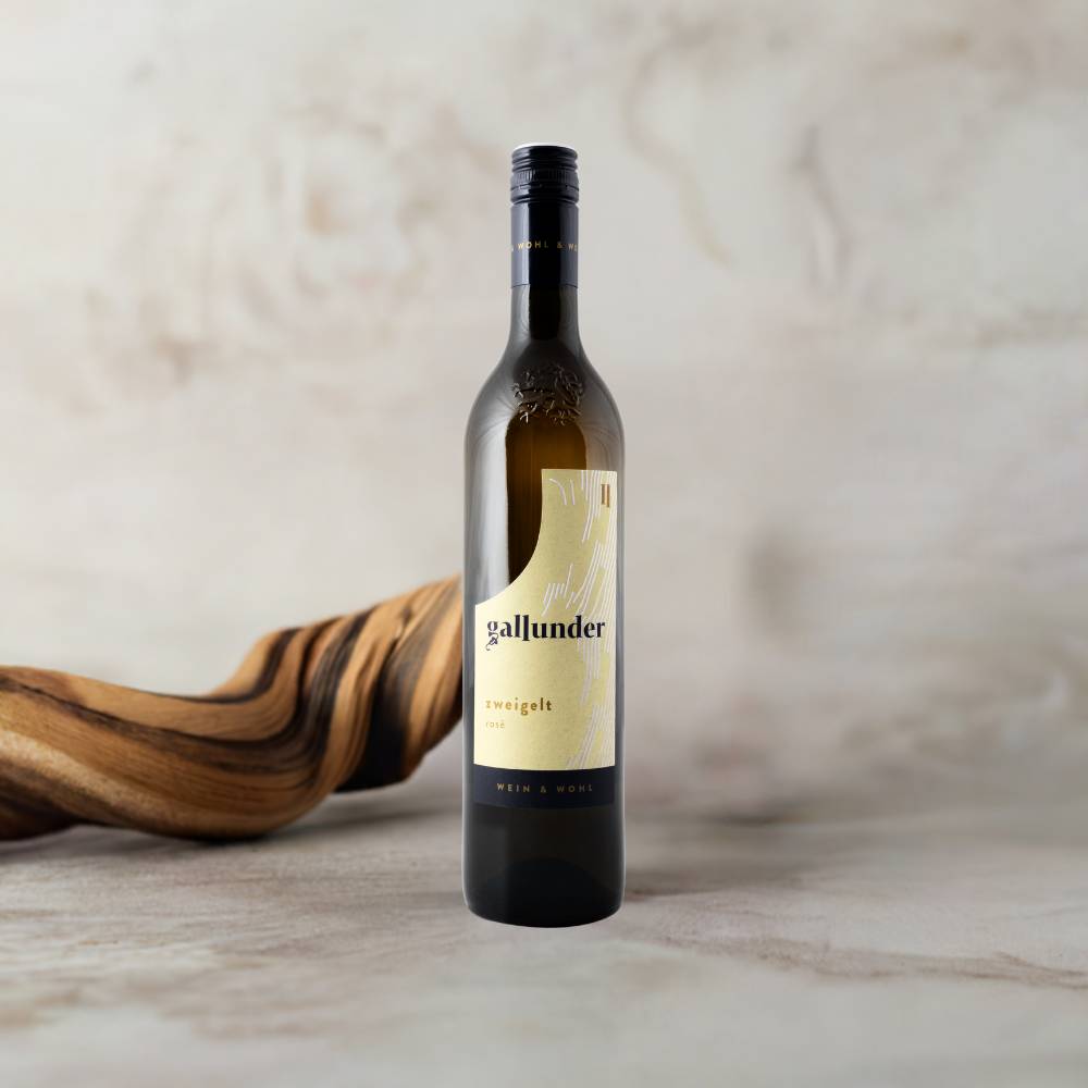 Zweigelt Rose Weinflasche auf Mamorplatte mit Holzwurzel im Hintergrund.